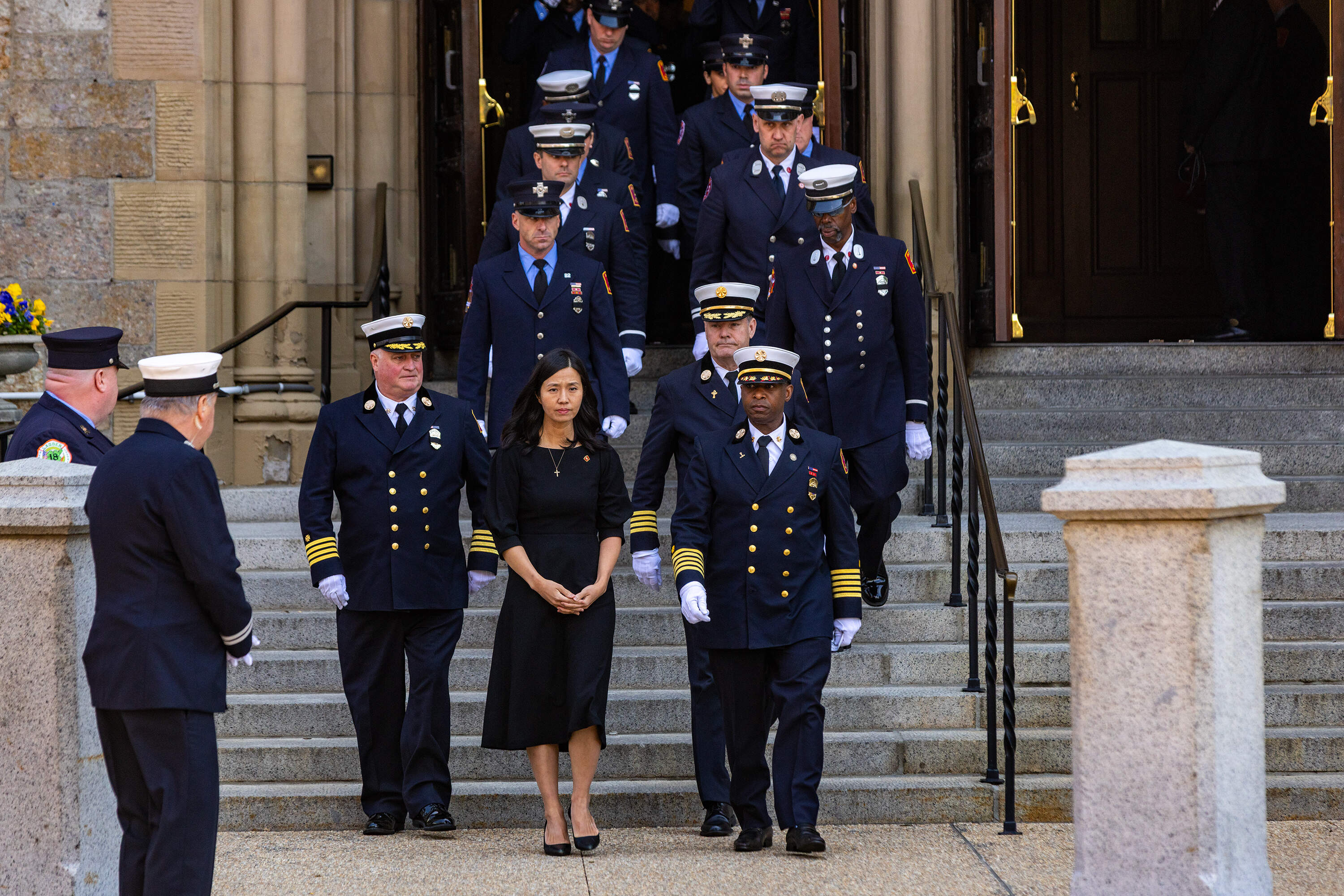 Mayor Michelle Wu is ushered out of the Cathedral of the Holy Cross by Boston Firefighters at the conclusion of the funeral service. (Jesse Costa/WBUR)