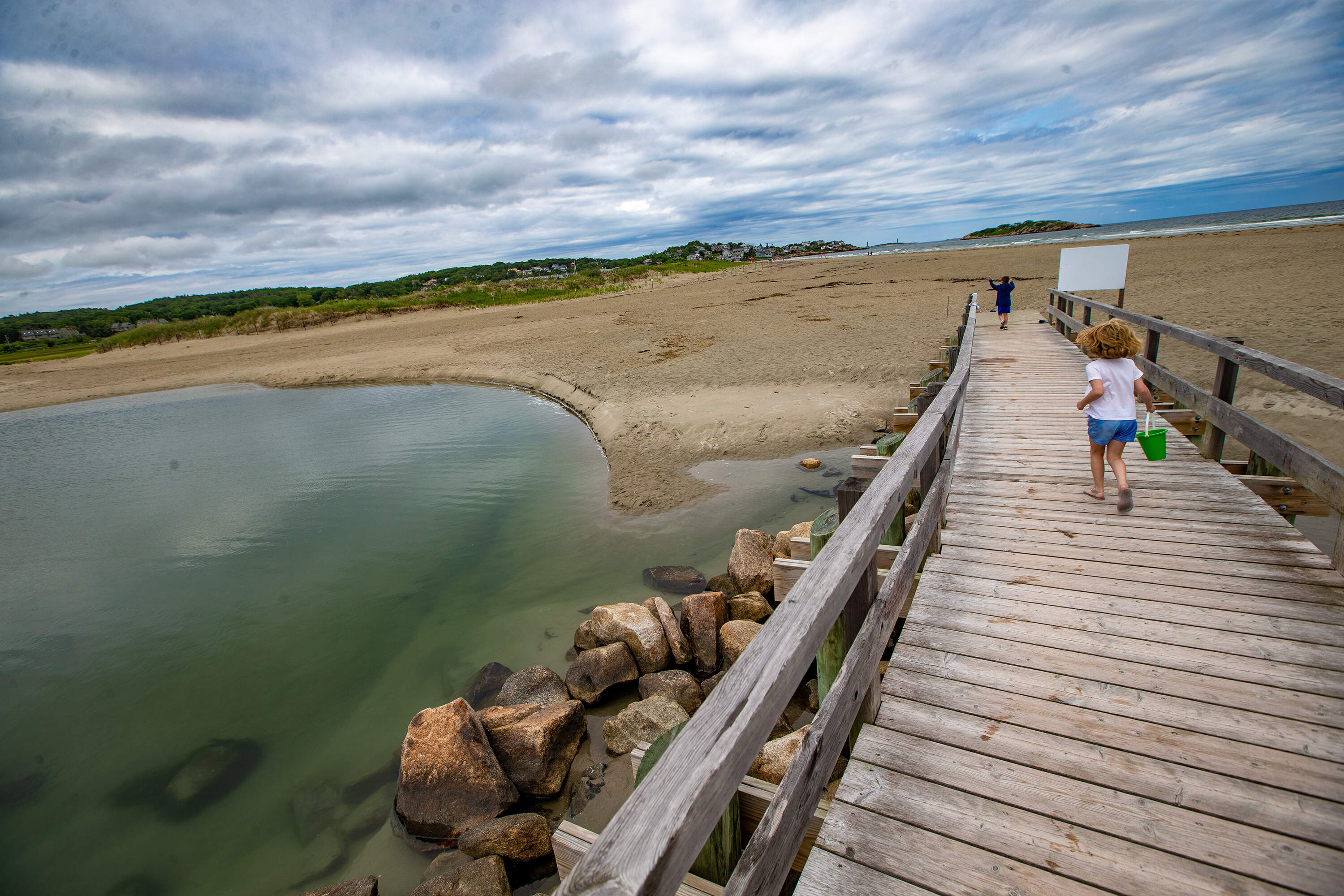 Two children run across the footbridge at Good Harbor Beach in Gloucester. (Jesse Costa/WBUR file)