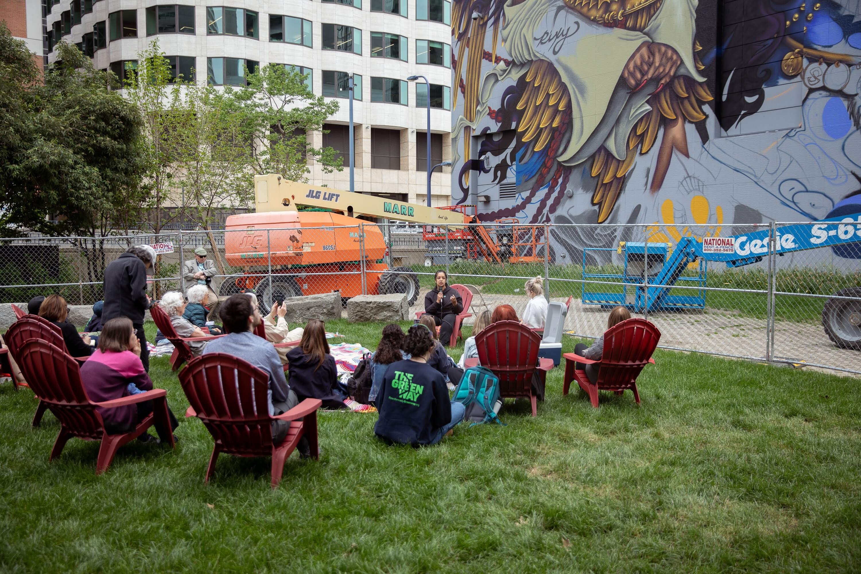 Rixy explains her mural to local community members during a lunchtime meet and greet by the in-progress Dewey Square mural on May 21. (Artemisia Luk/WBUR)