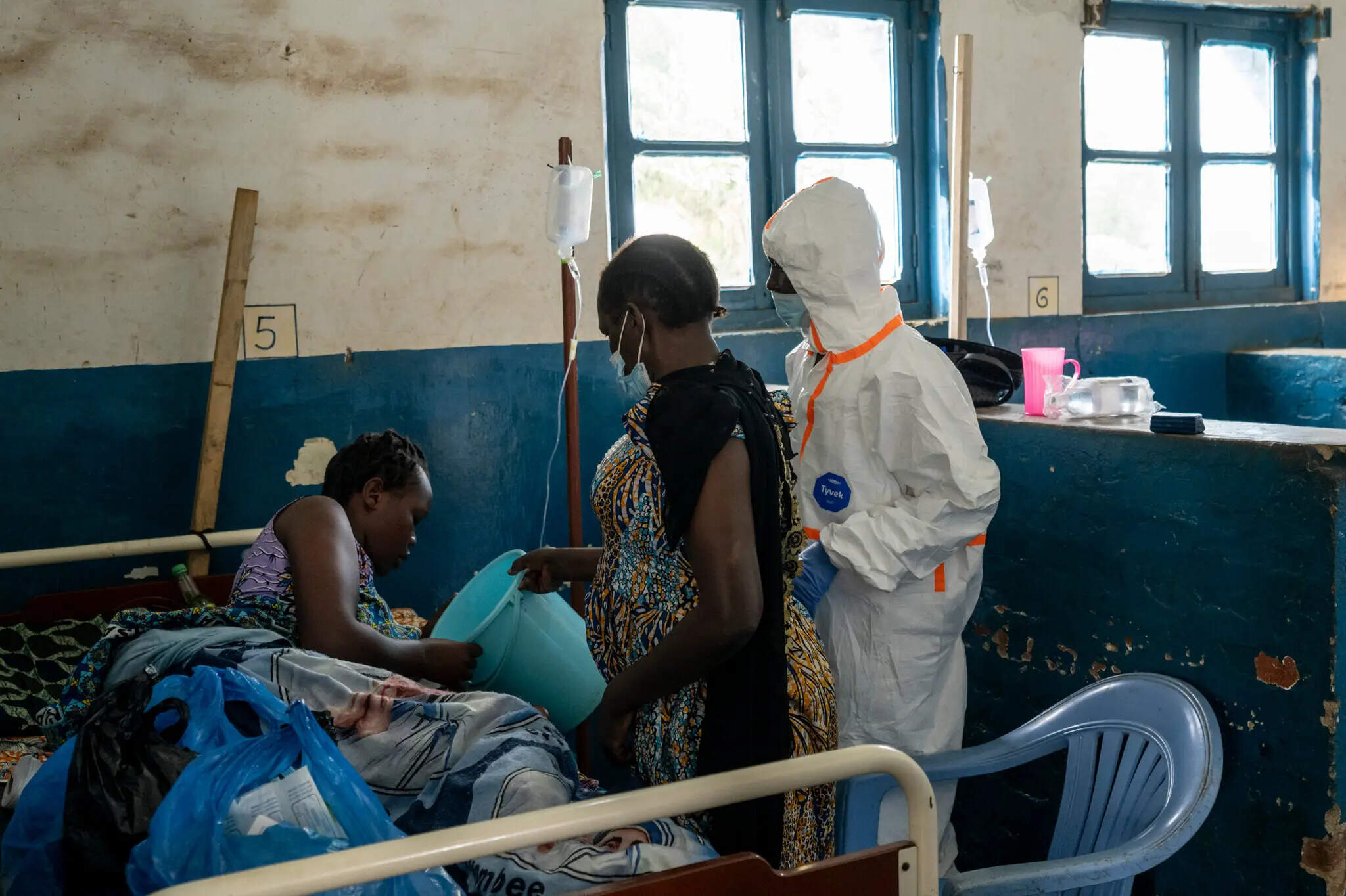 A relative and a medical worker caring for Christiane Bahati, an Ebola patient in Mongbwalu, shortly before she fell into a coma and died. (Courtesy of Arlette Bashizi for The New York Times)