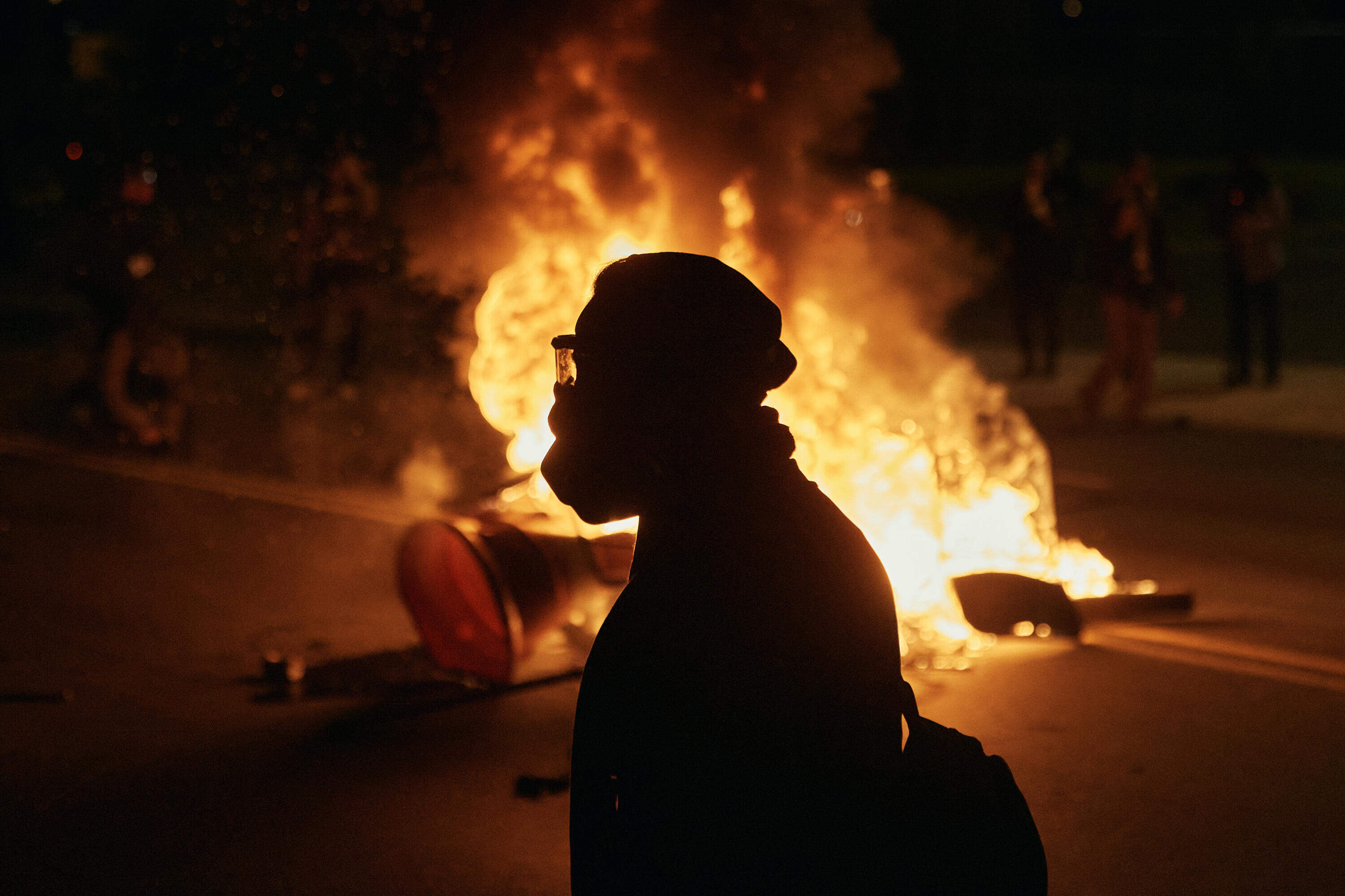 A man wearing protective gear walks in front of a burning barricade outside the Delaney Hall detention center during a protest against the transfer of detainees and federal immigration policies on Saturday, May 30, 2026, in Newark, N.J. (Andres Kudacki/AP)