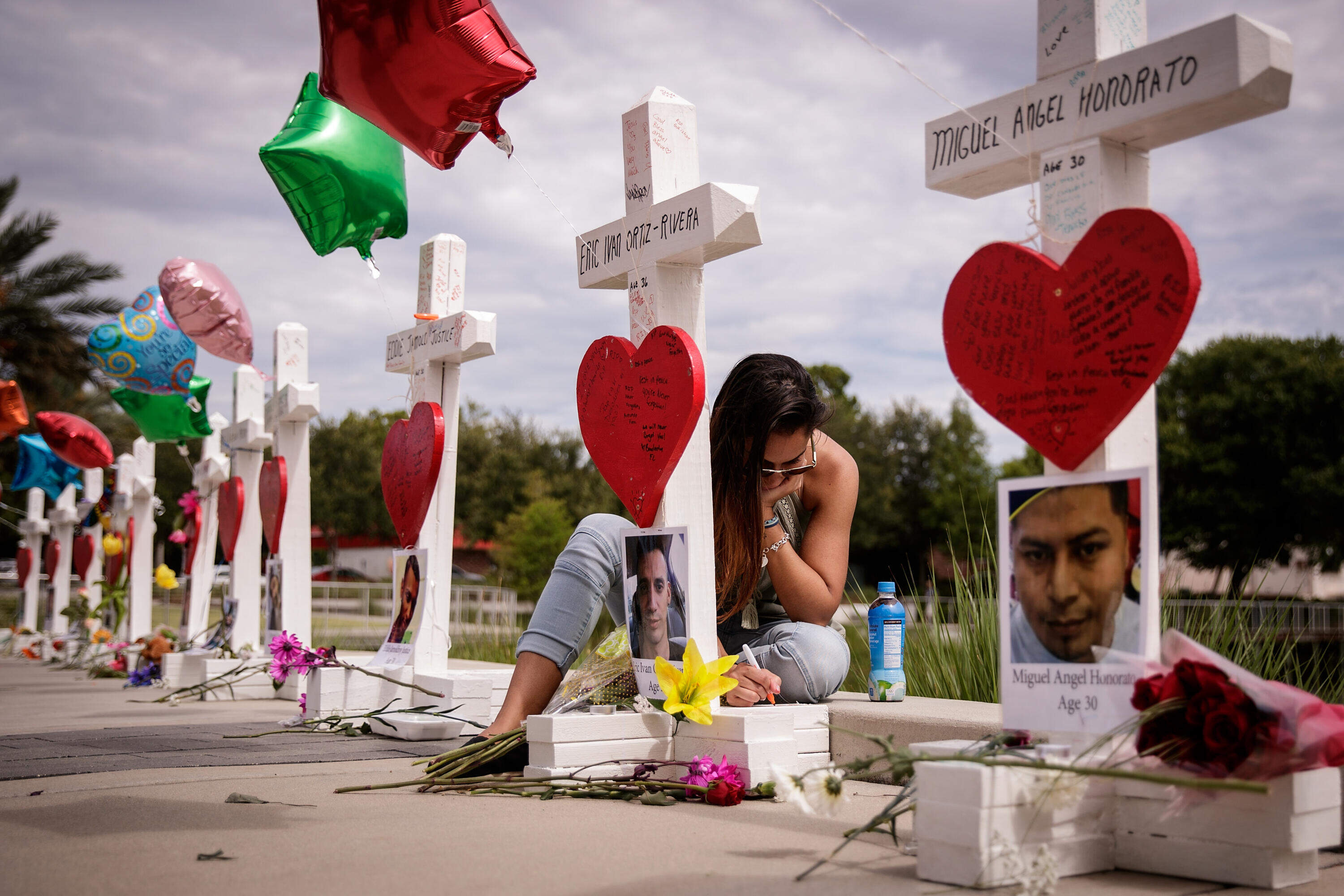 A woman writes a note on a cross for Eric Ivan Ortiz-Rivera at a memorial with wooden crosses for each of the 49 victims of the Pulse Nightclub, next to the Orlando Regional Medical Center, June 17, 2016 in Orlando, Florida. (Drew Angerer/Getty Images)
