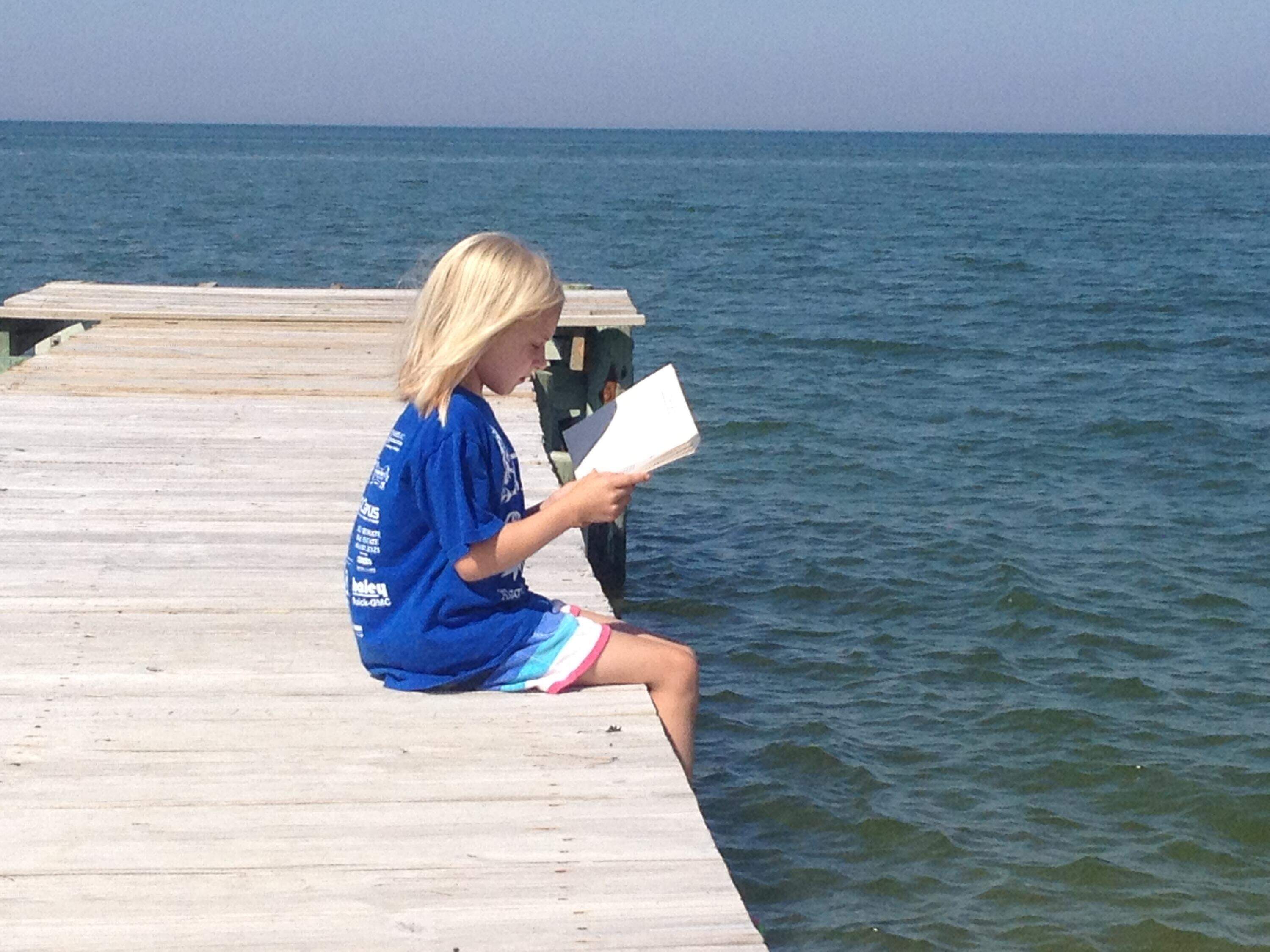 One of the author's children, reading on a dock ion Gwynn's Island, Virginia, in the summer of 2012. (Courtesy Kate Neale Cooper)