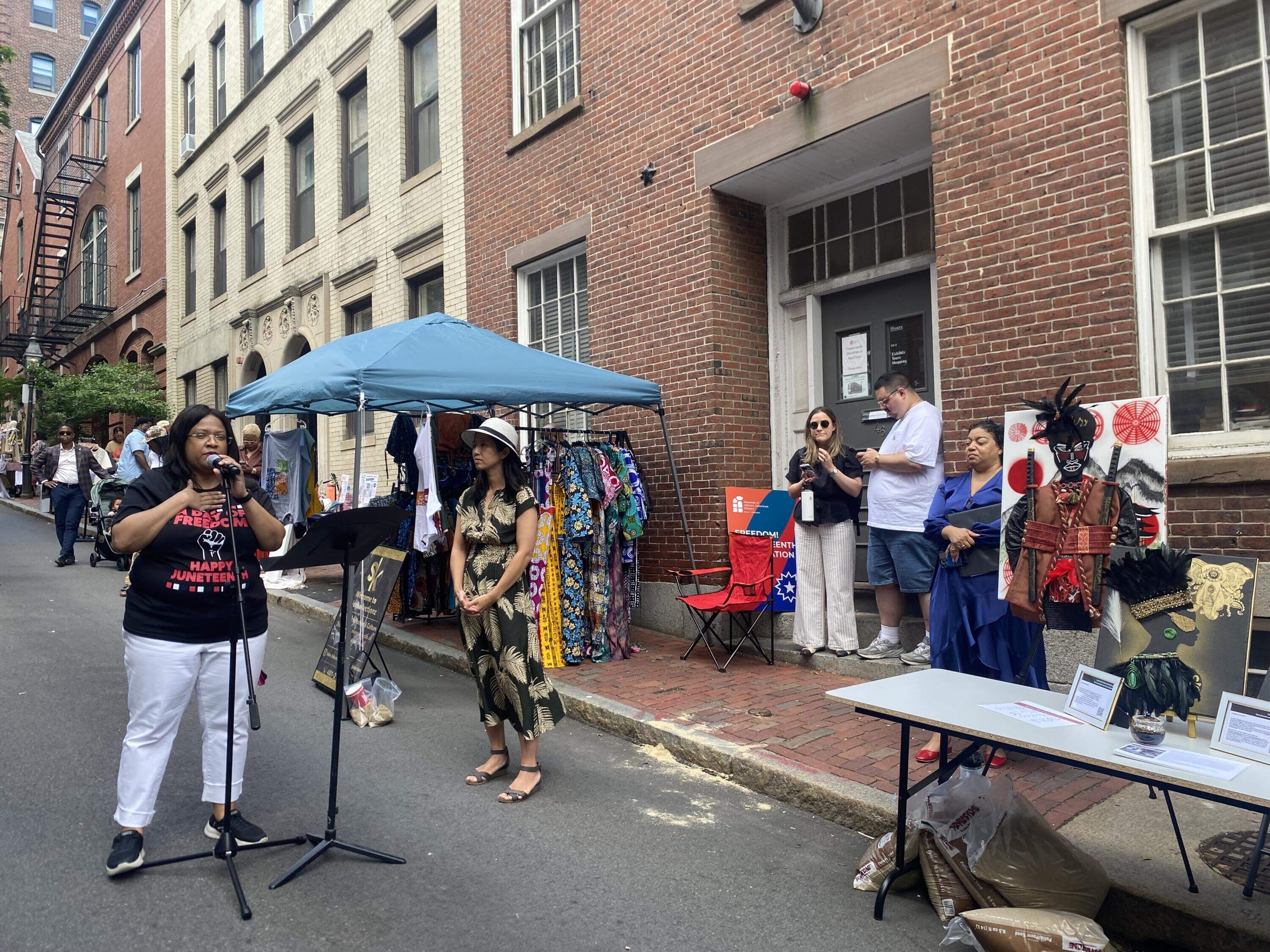Noelle Trent speaks at a Boston Juneteenth event as Mayor Michelle Wu stands nearby. WBUR/Suevon Lee