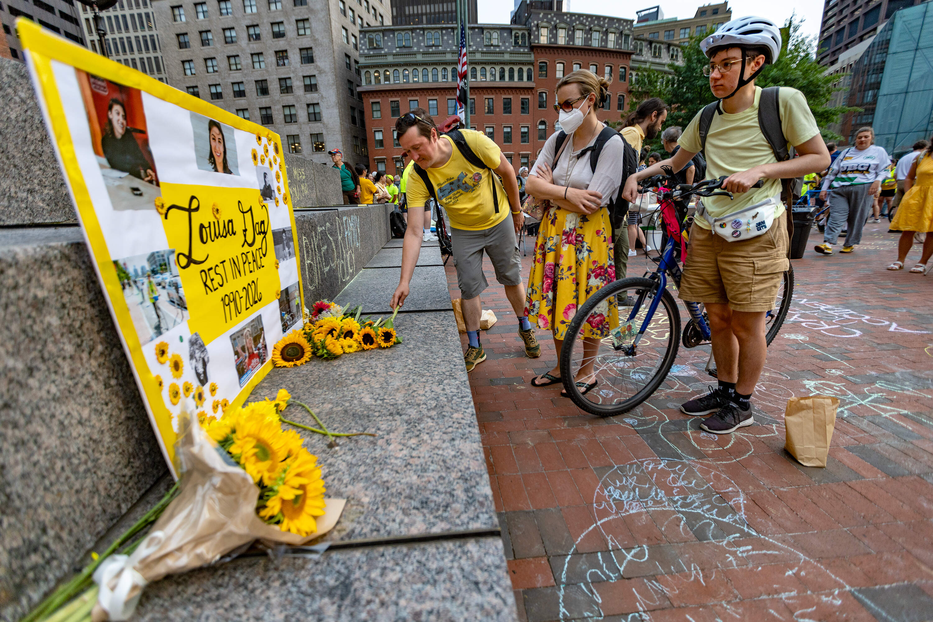 Vigil attendees pay their respects and leave flowers at a memorial set up for Louisa Gag at City Hall Plaza. (Jesse Costa/WBUR)