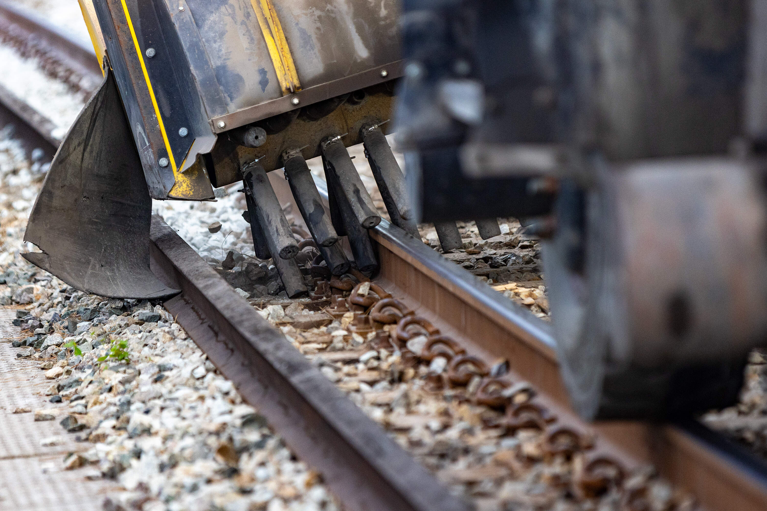 The Hi-Rail Gradall brushes the stone off the sides of tracks after stone has been secured beneath the railroad ties by the Tamper. (Jesse Costa/WBUR)