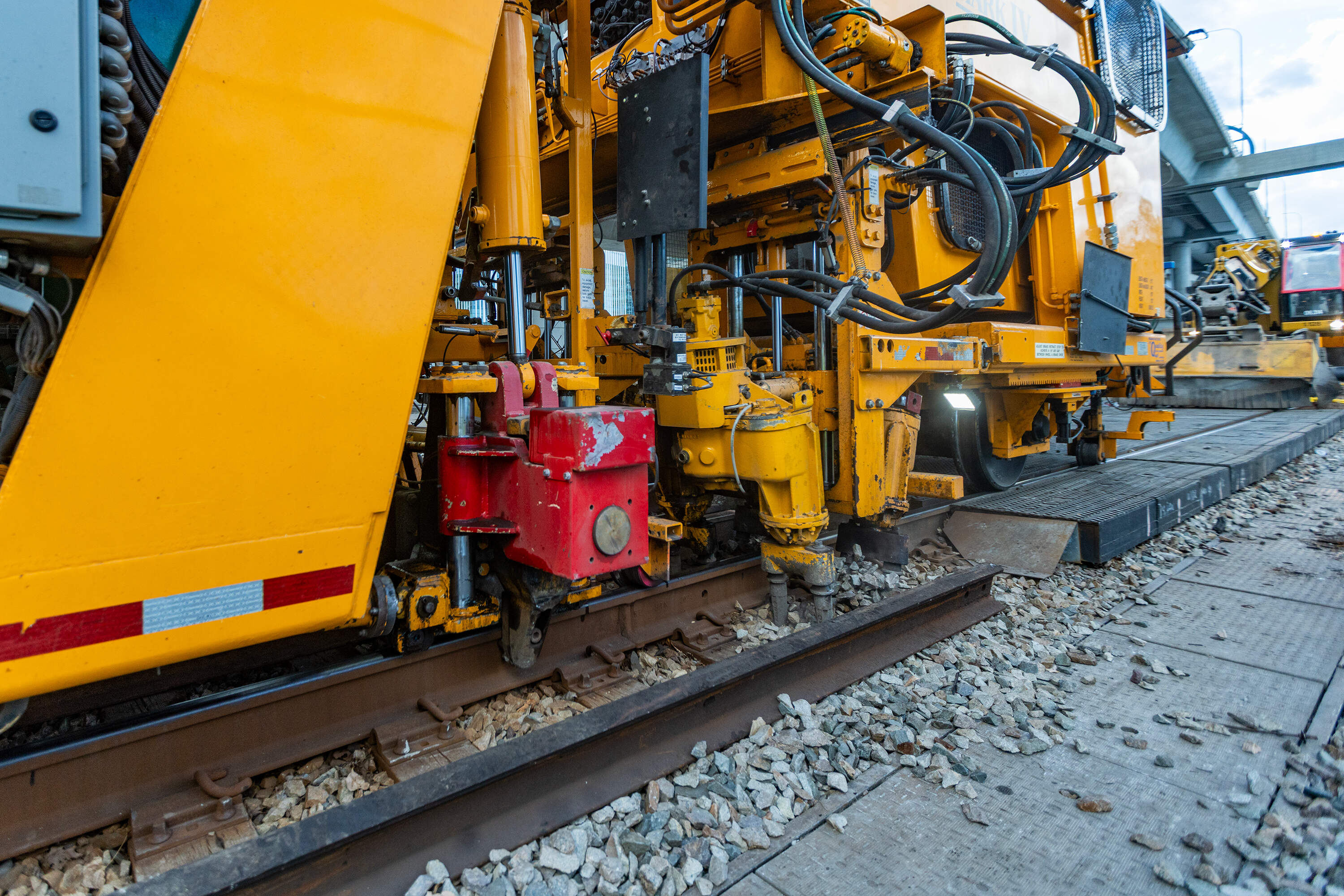 The railway tamping machine lifts the track and compacts the stone underneath each railroad tie. (Jesse Costa/WBUR)