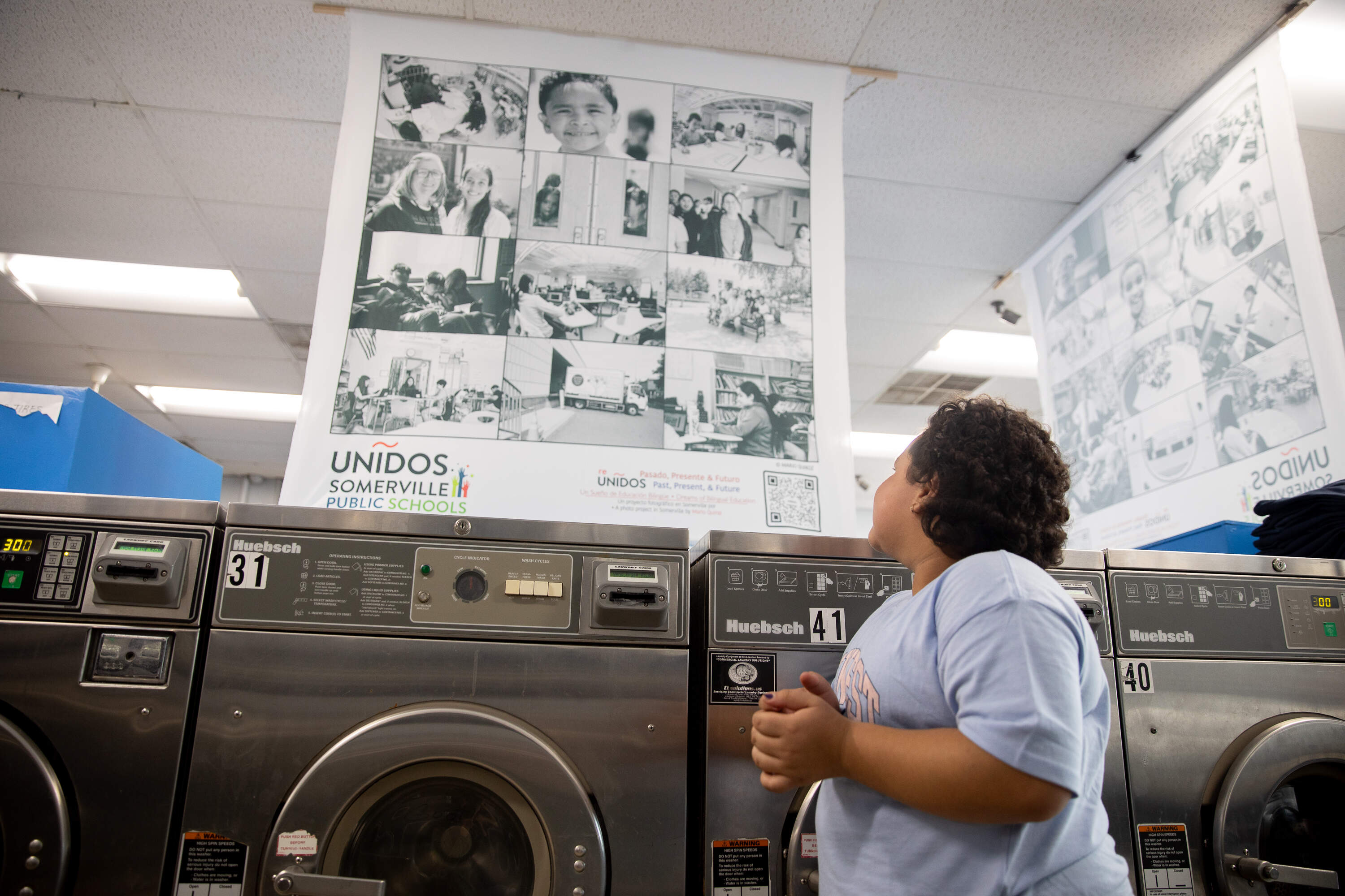 Sixth grader Jeydi Lazo Guevara looks at the portraits of her classmates and friends in the Unidos program. (Artemisia Luk/WBUR)